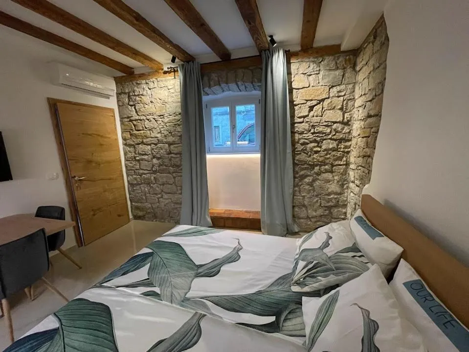 Apartma Leščur: postelja ob kamniti steni pod lesenimi tramovi