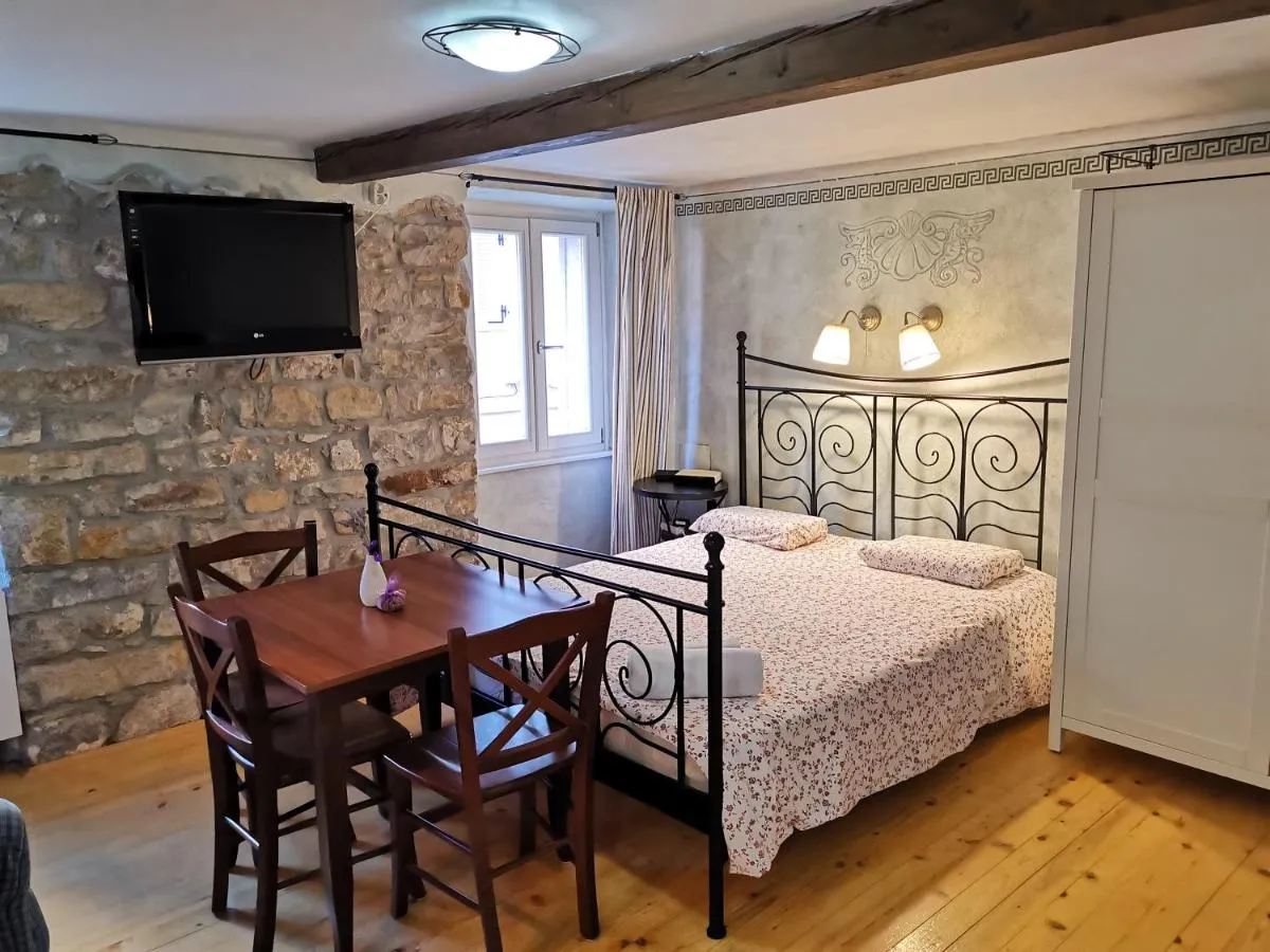 Apartma Mar: kovinska postelja, kamnita stena in televizor