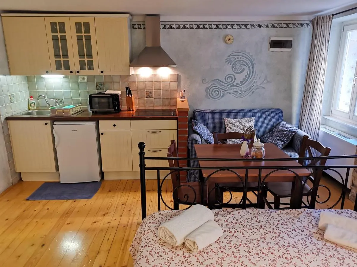 Apartma Mar: kovinska postelja, kuhinja in kavč pod poslikavo vala